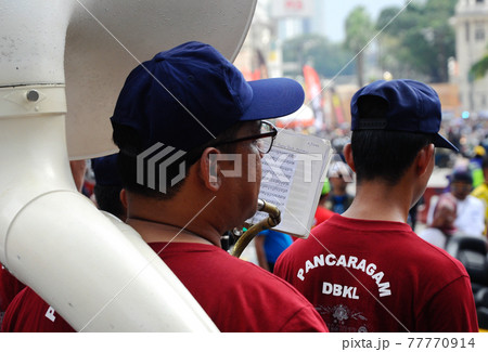 KUALA LUMPUR, MALAYSIA -FEBRUARY 22, 2017: Brass band player is playing a musical instrument while guided by musical notes. KUALA LUMPUR, MALAYSIA -FEBRUARY 22, 2017: Brass band player is playing a musical instrument while guided by musical notes. 77770914