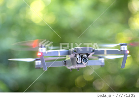 Drone aircraft with blurred fast rotating propellers and video camera flying in air. 77771205
