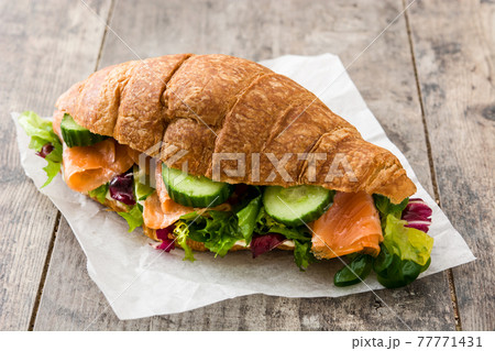 Croissant sandwich with salmon and vegetables 77771431
