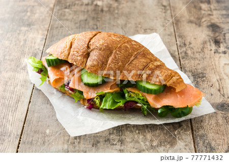Croissant sandwich with salmon and vegetables 77771432