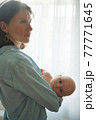 Mother with baby standing at home 77771645