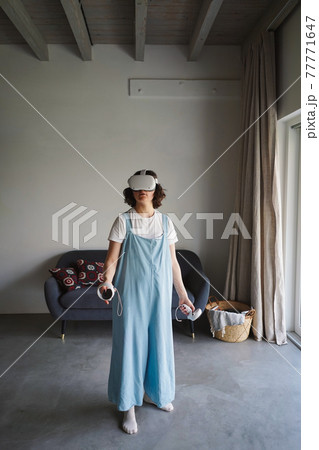 Woman in VR glasses experiencing virtual reality at home 77771647