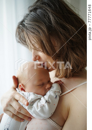 Mother kissing baby tenderly in forehead 77771648