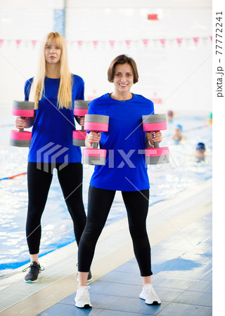 Two erobics trainers show the workout exercises in front of the pool. Two erobics trainers show the workout exercises in front of the pool. 77772241