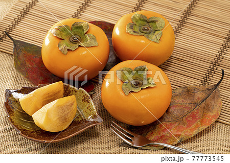 赤く色づいた葉の上に並べた柿 赤く色づいた葉の上に並べた柿 77773545