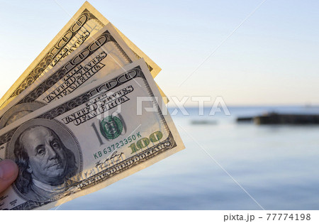 Three hundred dollar bills on background of sea surface. 100 dollar cash Three hundred dollar bills on background of sea surface. 100 dollar cash 77774198