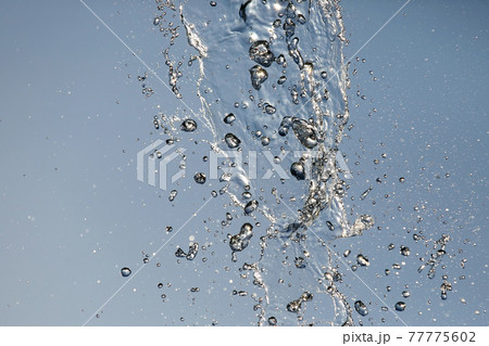 Splashes of flying water from the fountain against the blue sky Splashes of flying water from the fountain against the blue sky 77775602
