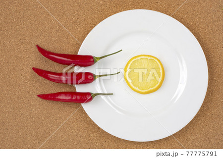 Red hot pepper with lemon on a white plate. Healthy vegetable food and vitamins 77775791