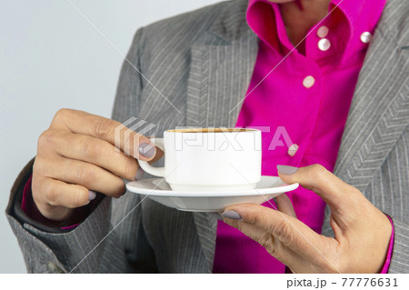 Business woman drinks coffee from a white cup close-up 77776631