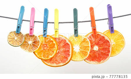 dried pieces of citrus fruits hang on clothespins 77778135