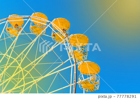 Sightseeing open ferris wheel in the amusement park on blue sky background with sunlight 77778291