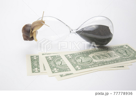snail crawls on an hourglass against the background of money.  77778936