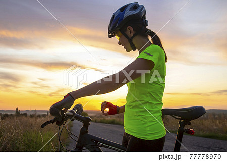 Beautiful girl cyclist holding in his hand the setting sun. Beautiful girl cyclist holding in his hand the setting sun. 77778970