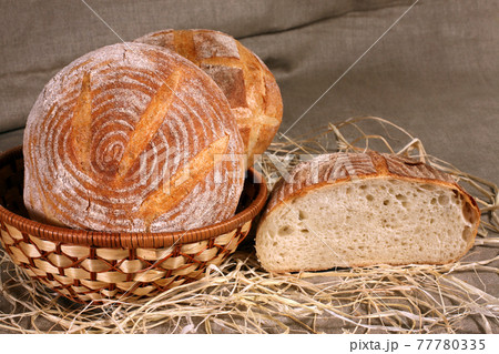 white bread lay in a straw basket on gray linen tablecloth 77780335