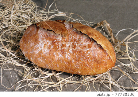 white bread lying in straw on grey linen tablecloth white bread lying in straw on grey linen tablecloth 77780336