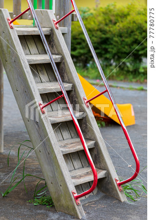 公園の黄色いすべり台と赤い手摺の木製の階段 公園の黄色いすべり台と赤い手摺の木製の階段 77780775