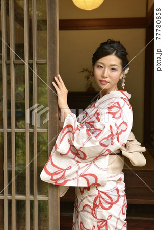 古民家の玄関先で微笑む美しい浴衣女性 77780858