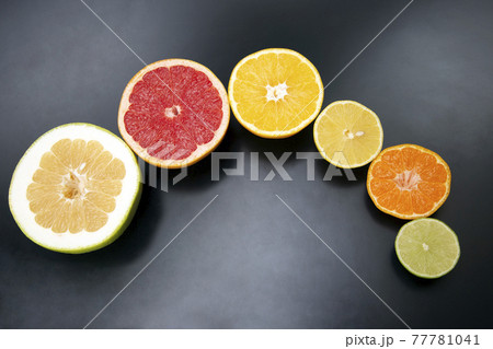 cut pieces of different citrus fruits on dark background cut pieces of different citrus fruits on dark background 77781041