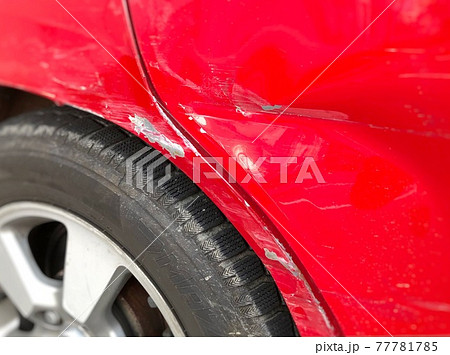 接触事故でボディに傷がついた赤い車の写真素材