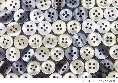 Plastic shiny buttons for clothes on a fabric background. Fashion and clothing. Factory industry Plastic shiny buttons for clothes on a fabric background. Fashion and clothing. Factory industry 77784069