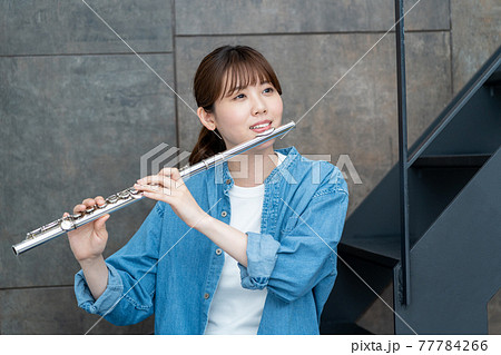 フルートを吹くカジュアルな女性 フルートを吹くカジュアルな女性 77784266