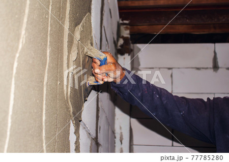 Close-up of a construction worker laying plaster for plastering the walls or walls of the house for house construction and building construction. Close-up of a construction worker laying plaster for plastering the walls or walls of the house for house construction and building construction. 77785280