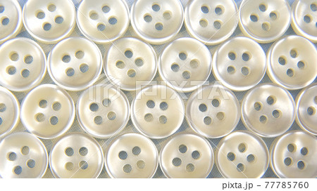Plastic shiny buttons for clothes on a fabric background. Fashion and clothing. Factory industry 77785760