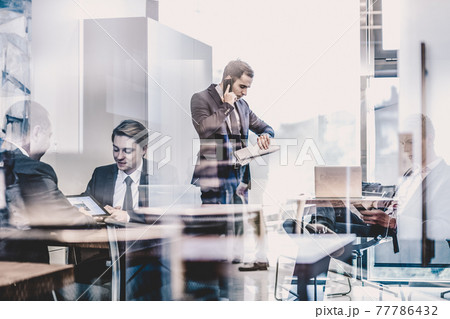 Businessman talking on a mobile phone on corporate office. 77786432