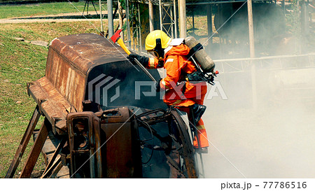 Firefighter fighting with flame using fire hose chemical water foam spray engine. Fireman wear hard hat, body safe suit uniform for protection. Rescue training in fire fighting extinguisher Firefighter fighting with flame using fire hose chemical water foam spray engine. Fireman wear hard hat, body safe suit uniform for protection. Rescue training in fire fighting extinguisher 77786516