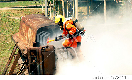 Firefighter fighting with flame using fire hose chemical water foam spray engine. Fireman wear hard hat, body safe suit uniform for protection. Rescue training in fire fighting extinguisher Firefighter fighting with flame using fire hose chemical water foam spray engine. Fireman wear hard hat, body safe suit uniform for protection. Rescue training in fire fighting extinguisher 77786519