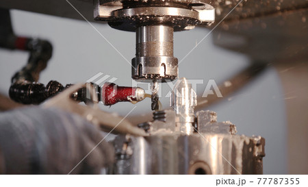 Produces metal detail in factory. Machine tools for metal working. A metal workpiece is machined by an electric machine. Cutting metal modern processing technology. Coolant and lubrication. 77787355