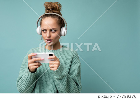 closeup photo of beautiful sad young woman wearing blue sweater isolated over blue background 77789276