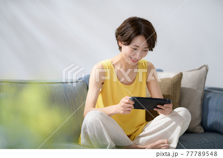 ミドル女性　ソファー　ゲーム 77789548