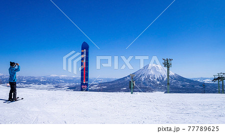 [パノラマ] 晴れた日のスキー場で写真を撮るスキーヤー (ニセコ、北海道) 77789625
