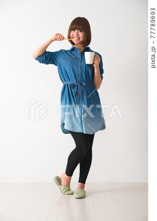 カップを手に持ち歯を磨く若い女性 カップを手に持ち歯を磨く若い女性 77789693