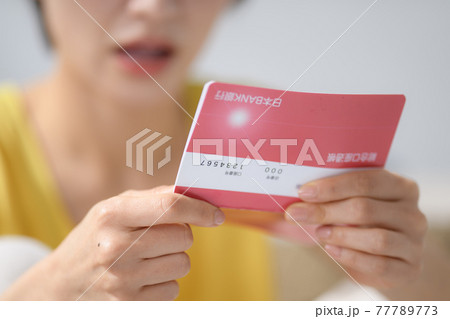 ミドル女性　手元　通帳　悩む 77789773