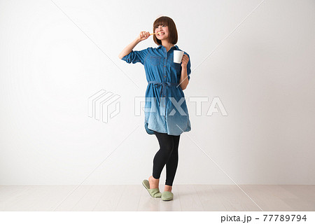 カップを手に持ち歯を磨く若い女性 カップを手に持ち歯を磨く若い女性 77789794