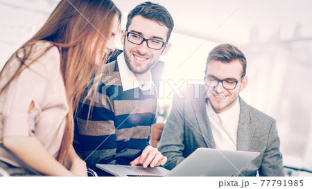 friendly business team working on laptop and discussing business matters 77791985