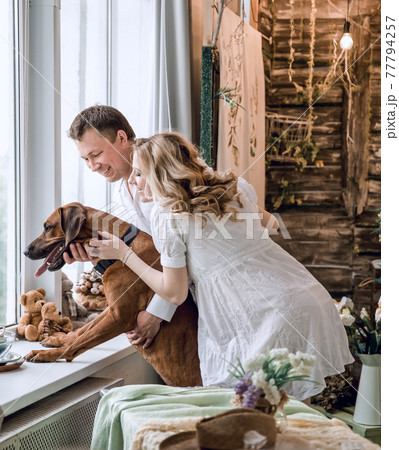 handsome man and his dog looking through the window in his apartment handsome man and his dog looking through the window in his apartment 77794257