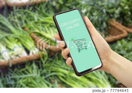 Online grocery delivery app in a mobile phone. Food market service in smartphone. Grocery delivery background concept. Shopping cart. Online grocery delivery app in a mobile phone. Food market service in smartphone. Grocery delivery background concept. Shopping cart. 77794645