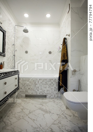 Modern bathroom with marble tiles, luxurius wardrobe and white toilet 77794794