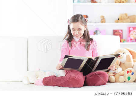 girl reading a book sitting on the couch in the nursery girl reading a book sitting on the couch in the nursery 77796263