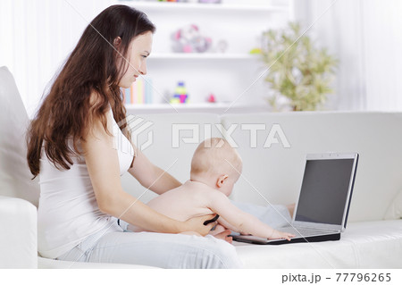 young mother plays with the baby and talking on a mobile phone young mother plays with the baby and talking on a mobile phone 77796265