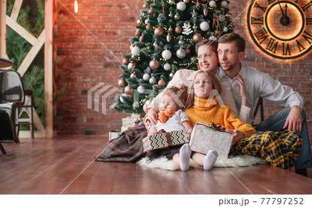 family with Christmas gifts in a cozy living room family with Christmas gifts in a cozy living room 77797252