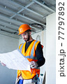 Male worker holding a paper apartment plan indoor before repair room  77797892
