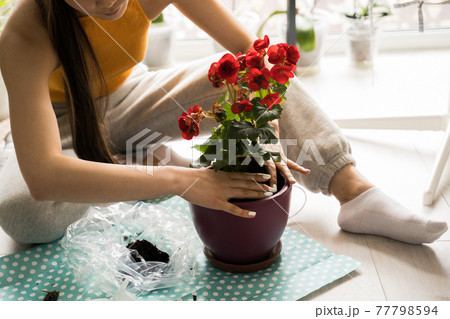 Woman looking at green plants and smiling while spending time at home 77798594