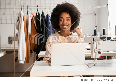 Woman looking to the camera while working at her laptop computer 77799318