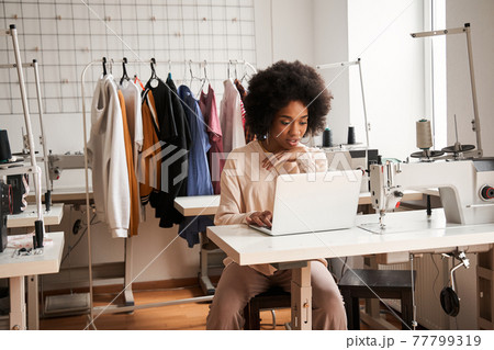 Woman looking attentively at the laptop and chatting with clients while creating Woman looking attentively at the laptop and chatting with clients while creating 77799319