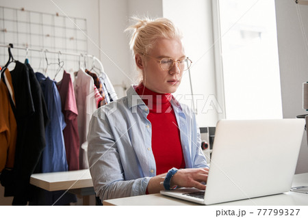 Man looking attentively at the laptop screen while creating new collection 77799327
