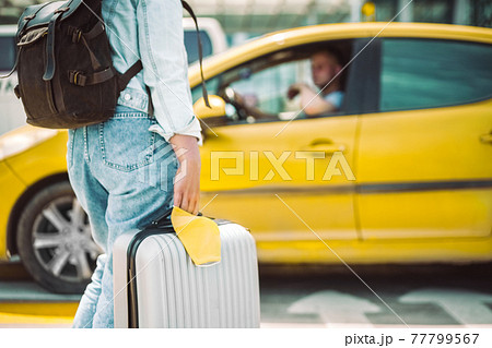Woman waiting for taxi with face mask and travel case Woman waiting for taxi with face mask and travel case 77799567
